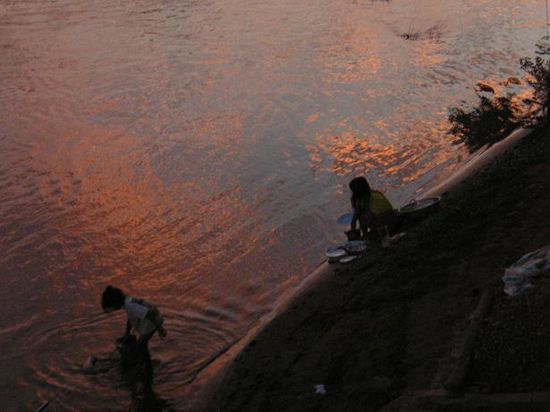 Wasser holen und Geschirrspuehlen bei Sonnenaufgang vor unserem Bungalow