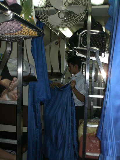 Zugpersonal baut die Schlafkojen hinter blauen Vorhaengen auf