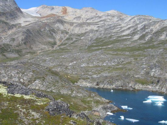 Unser Zeltplatz am Fjord (man beachte die winzigen gelben Punkte unterhalb des braunen Felsen in der Nähe des Wassers).
Auf den Berg mit den braunen Ablagerungen sind wir heute gestiegen.