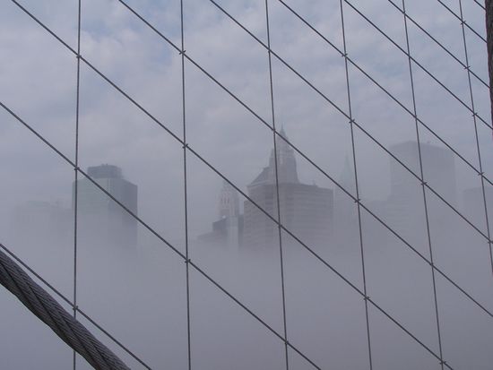 Manhattans Spitze durch Nebel und Stahlseile der Brooklyn Bridge