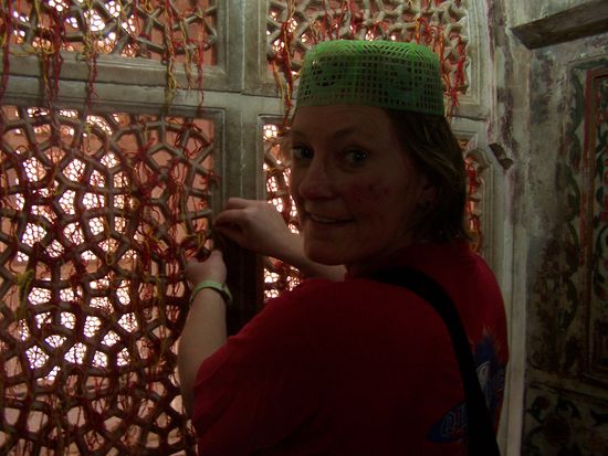 Man muss sich so eine bescheuerte Plastikkappe aufsetzen, um ins Innere des Heiligtums zu kommen. Man kann auch ein Stück Stoff kaufen und ein paar Blumen, alles wird auf eimen Sarkophag verteilt. Akbar ??? (Wieder mal nicht aufgepasst...) 3 Rot-gelbe Fäden kann man dann an diesem Fenster zusammenknoten und sollte sich dabei etwas wünschen. 3 Wünsche werden erfüllt, wobei einer nicht für einen selbst sein darf ! OK, ich glaube ja gerne alles und wünsche und knote !