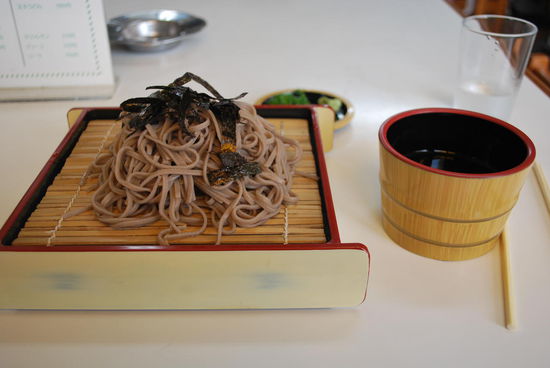 Nein, es schmeckt mir nicht. Das sind kalte Soba-Nudeln aus Buchweizenteig mit Seetang obendrauf. Durch die Tunke werden sie auch nicht besser, aber ich esse auf. Der Hunger treibt es rein.