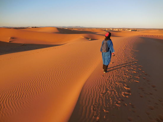 Wir nähern uns dem Headquarter für die Touren - jetzt kommt die Souvenirverkaufs-Nummer: Der Rucksack wird ausgepackt, es sind Souvenirs drin, die kein Mensch will. 
Und dennoch: Ich kaufe ihm eine schreckliche Seifenschale aus "Wüstengestein" ab, einfach nur für seine Hilfe während des "Spazierganges" durch die Wüste und seine "Unterhaltung" - verständigen konnten wir uns selbst auf französisch praktisch nicht, aber er hat mir seine Hand geboten, Fotos von mir gemacht, mich aus dem Sand wieder hochgezogen und mich wie ein Kamel vorwärts gepeitscht. Er hat geduldig neben mir im Sand gesessen, während ich einfach nur aus der Puste war. Schlicht: Er war süß ! Und vielleicht 17 Jahre jung... Ich habe andere Gruppen mit Berbern im Sand sitzen sehen, die partout nichts kaufen wollten. OK, kann ich auch verstehen, kein Mensch braucht das Zeug, aber die brauchen das Geld, und wegen 3 EUR Aufstand machen ? Das werde ich nie verstehen !
Dies ist das Schicksal der Seifenschale seither gewesen: Sie verschwand zunächst für viele Monate in einem Schrank und ward nicht mehr gesehen. Irgendwann stieß ich zufällig wieder auf das Teil und versuchte, es unbemerkt meiner Mutter unterzujubeln: Ich habe sie einfach in der Wohnung meiner Eltern irgendwo stehen lassen, in der Hoffnung, sie endgültig los zu sein. Nein, meine Mutter fiel praktisch sofort über das Ding, hatte selbstredend sofort mich in "Verdacht" und verfrachtete das gute Stück zurück in meine Wohnung. Zurück in den Schrank, wo sie sich noch heute befindet. Tja. Nach 10 Jahren, also 2023 wird sie entsorgt. Solange ist bei mir die Halbwertzeit von erinnerungsträchtigen Souvenirs...