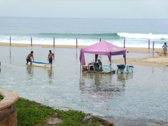 In der Frueh nachdem die Flut den Strand ueberschwemmt hat...der Thai sammelt seine Liegen mit dem Boot ein... 
