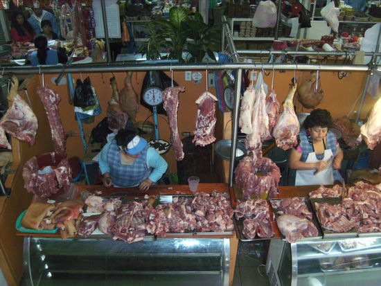 Am Fleischmarkt geht es zünftig zu - die Verkäuferin rechts wetzt die Messer während jene links das Fleisch lieber direkt mit ihren schmutzigen Fingern zerlegt... 