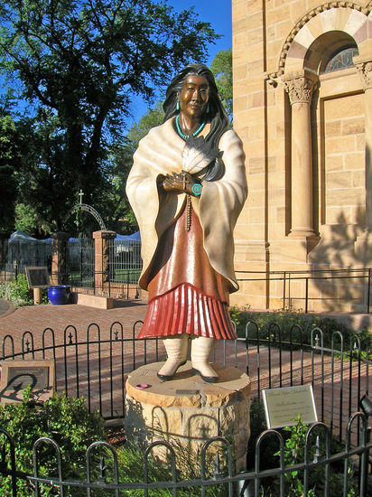Bronzestatue der Indianerin Kateri - 1656-1680 - vor der Kathedrale des Hl. Franz von Assisi in Santa Fe - New Mexico.
Kateri Tekakwitha wurde nach dem Tod ihrer indianischen Eltern von Verwandten erzogen. Sie lehnte mehrfach eine Heirat ab und gelobte Jungfräulichkeit. Als 20-jährige wurde sie von einem Jesuitenpater getauft und schloss sich einer Missionsstation der Jesuiten bei Montréal an. Dort führte sie ein Leben der Buße und des Gebets.
Nach Kateris Tod ereigneten sich Wunder und Heilungen. Ihre Gebeine sind im Reservat der Mohawk-Indianer in Caughnawaga / Kahnawake aufbewahrt, sie wird als die "Lilie der Mohawks" verehrt.
Kateri wurde 1980 als die erste Indianerin von Papst Johannes Paul II. seliggesprochen.