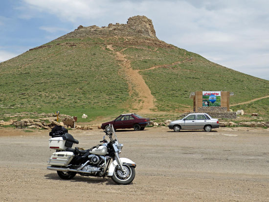 Die Fahrt führt uns ins Gebirge, wir kommen zum Zendan-e Soleiman (Salomons Gefängnis). Dies ist ein runder 110 m hoher Kegel mit einem 100 m tiefen und 70 m breiten Krater. Der Kegel soll durch Ablagerungsvorgänge von Mineralien entstanden sein. Hier stand in mannäischer Zeit (830-650 v. Chr.) ein Heiligtum, dessen Mauerreste sich ringförmig um den Krater ziehen. Eine Treppe führt zu den obe-ren Terrassen. Vermutlich wurden früher Opfergaben in den Krater geworfen.
Einer Legende zufolge soll der Prophet Salomo eine Zeit lang in dem Felskegel gefangen gewesen sein. Nach manchen eher denkbaren Ansichten war das Gebilde einstmals ein Feuertempel oder ein Grab, möglicherweise des Kambyses, des Sohnes und Nachfolgers des Kyros.