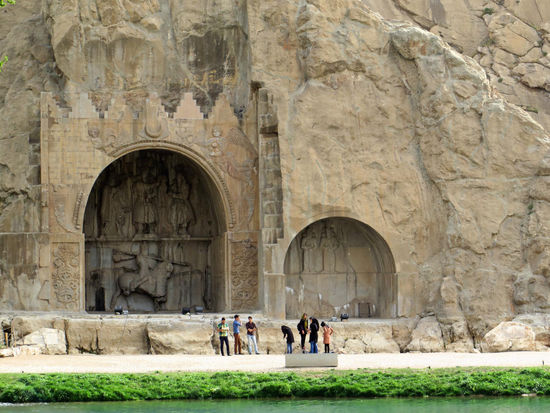 Kermanshah - Taq-e Bostan
Die Grotten befinden sich am Fuß des Felsens gleichen Namens. Hier steht eine sassanidische Anlage, bestehend aus Grotten und Reliefs, die bei einem Quellsee angelegt wurden, mitten im Herzen des Zagros-Gebirges, wo es fast 1700 Jahre lang Wind und Regen ausgesetzt war. Bewusst wählten die sassanidischen Könige ein schönes Umfeld entlang eines Rastplatzes der historischen Seidenstraße. Die Reliefs liegen neben einer heiligen Quelle, die in ein Becken am Fuße einer Klippe mündet. Die hier zu sehenden sassanidischen Werke zeigen mit ihren Bildern die Macht, religiöse Tendenzen, Ruhm, Ehre, die Größe des Könighofes, den Kampf- und Spielgeist, Festlichkeiten, Freude und Jubel.