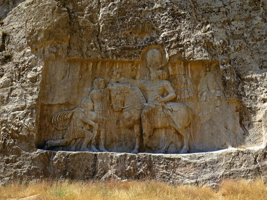 Naqsh-e Rostam
Dies ist eine archäologische Stätte, sechs Kilometer nördlich von Persepolis. Hier befinden sich 4 Gräber (Nekropole) der achämenidischen Großkönige sowie eine Reihe sassanidischer Felsreliefs am Hoseyn Kuh-Berg.