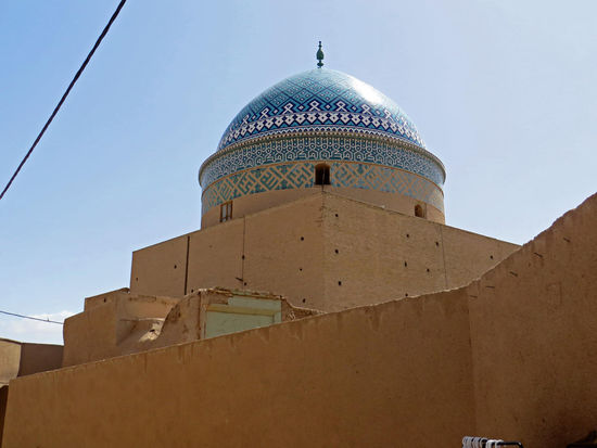 Yazd - Besonders sehenswert in der Nähe ist das Mausoleum Rokn od-Din - dieses hat eine türkisfarbene Kuppel mit blauem Gitternetz. Der Grabbau zeichnet sich durch die prächtigen, an florale Teppichmuster erinnernden Ausmalungen der Innenkuppel aus, um die ein Schriftband läuft. Hier ist Rokn od-Din beigesetzt, der die Freitagsmoschee gründete und viele Stiftungen schuf. Das Mausoleum ist von allen erhöhten Punkten in Yazd zu sehen und etwa 700 Jahre alt.