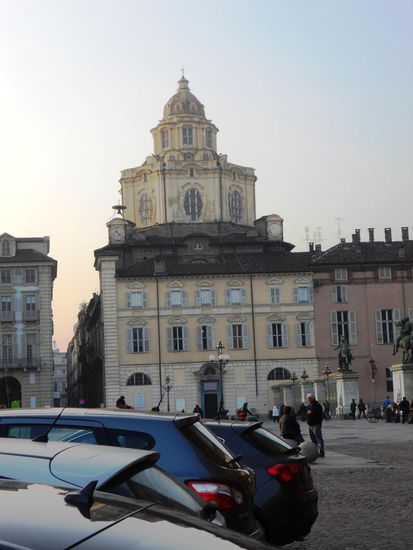 Die Kirche San Lorenzo auf der Piazzetta Reale, erbaut von 1668-1680 durch Guarino Guarini, ist wegen der Originalität eines der hervorragendsten Bauwerke des ital. Barocks in Turin. Ihre Pracht verbirgt sich hinter schlichtem Mauerwerk. Ihre Fassade ist die eines typischen Turiner Wohnhauses und nicht die eines religiösen Gebäudes. Diese wenig traditionelle Kirche lieben die "Turinesi" mehr als ihren Dom. Nur die Kuppel fällt auf. Sie ist der Clou, sorgen doch ihre Öffnungen für wechselnde Lichteffekte. Wer drinnen genauer empor schaut, erkennt ein böses Gesicht. Nur ein Zufall? "Manche meinen, der Teufel blicke von oben herab," flüstert Stadtführerin Emanuela Moroni.