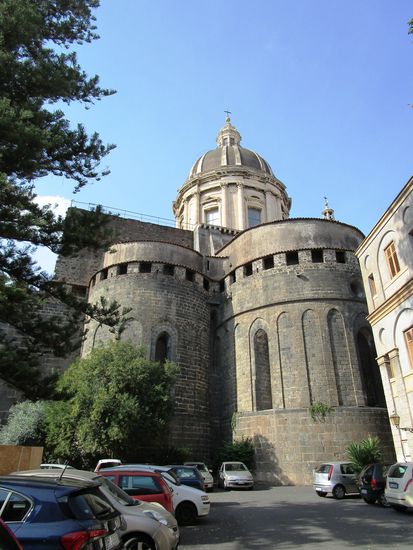 Von der ehemals von dem Normannen Roger I gebauten Kirche sind aus dem Hof des erzbischöflichen Palastes einige gut erhaltene Teile zu sehen: die Umgrenzungsmauern der Vierung, die beiden Türme und die drei halbrunden Apsiden, alles bestehend aus großen schwarzen Lavasteinen, aus ehemaligen kaiserlichen römischen Gebäuden stammend. Die Schiess-Scharten erinnern daran, dass die Kirche als Wehrkirche errichtet wurde. Ganz schön mächtig muss das Gebäude damals ausgesehen haben. Die Apsiden wurden im 20. Jahrhundert vom Barockschmuck befreit, sodass man einen Blick auf die ursprüngliche Bauweise des Normannendoms werfen kann.