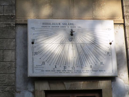 Wir entdecken hier auch die Marmor-Sonnen-Uhr von Salvatore Franco, Priester und Wissenschaftler. Die Sonnenuhr von Salvatore Franco wurde zwischen 1888 und 1890 mit der Finanzierung von Monsignore Antonino Cafeteria, Weihbischof von Catania realisiert, als Kardinal Benedetto Dusmet Bischof in Catania war. Im Laufe der Zeit wurde dieses Kunstwerk vernachlässigt, von der Wand entfernt und lag dann 82 Jahre verloren in einer Ecke des Hofes des Erzbischöflichen Palastes. Erst 2012 wurde die kunstvolle Sonnenuhr endgültig restauriert, repariert und wieder ihrem ursprünglichen Zwecke zugeführt. Sie schmückt nun wieder eine Wand des Palastes und Anneken erklärt uns genau, welche Stunde es geschlagen hat, aber erst, nachdem sie ihre eigene Uhr zu Rate gezogen hat.