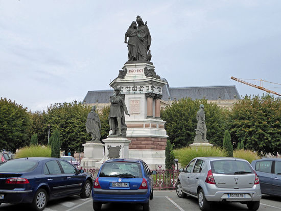 In der Mitte des Platzes sticht uns sofort das Monument des Trois Sièges de Belfort – Denkmal für die drei Belagerungen – ins Auge. Auch dieses Denkmal hat Bartholdi geschaffen. Es stellt Frankreich und die Stadt Belfort mit ihren drei Verteidigern dar – Legrand, Lecourbe und Denfert-Rochereau. — – hier:  Place de la République, Belfort, Frankreich .