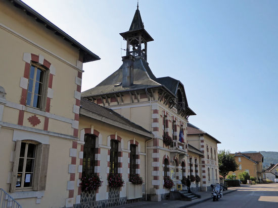 Servance. Wir wollen das Rathaus, welches einen interessanten Glockenturm besitzt fotografieren. In der Mairie ist auch die Schule untergebracht. Das Gebäude wurde 1906 errichtet und ist als Monument historique eingestuft.