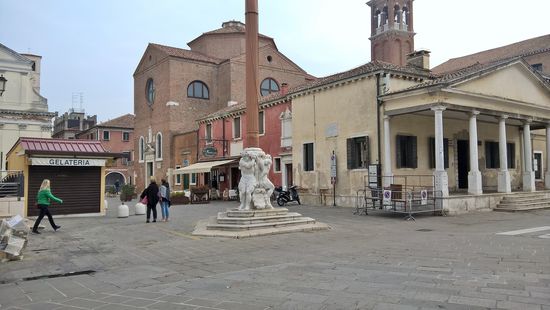 Standarte – Stendardo. Der Marmorsockel, der die Standarte trägt, es handelt sich hier um drei Zyklonen, denen der Volksmund eindrucksvolle Namen gegeben hat. Rechts daneben Loggia dei Bandi