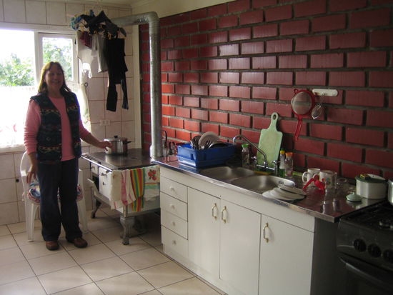 nancy in der kueche. ueber dem holzherd haengt die waesche der familie, rechts ist unser fruehstuecksgeschirr.