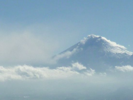 Der Cotopaxi von Westen gesehen (aus ca. 4.000 Meter Höhe):
die Aschewolke senkt sich Richtung Quito ins Tal, wird dann aber wieder hochgetrieben, um über den "echten" Wolken als gigantischer Smog weiter Richtung Pazifik zu verwehen.
Man beachte die die obersten 1000 Höhenmeter des Vulkans: das ist der Gletscher, der den Menschen hier solche Sorgen bereitet. Meine Vermutung als Laie dazu: die befürchtete Zerstörung durch Lahare (Wasser-/Schlamm-/Schuttlawinen) dürfte zumindest ein wenig "schwächer" ausfallen als vor 140 Jahren, einfach, weil der Gletscher nicht mehr so groß ist. Reine Laien-Vermutung 