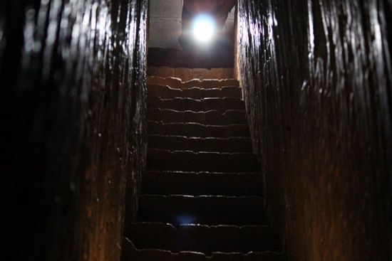eine enge dunkle Treppe mit steilen Stufen und niedriger Decke führt hinauf auf die Terrasse diese Pagode.