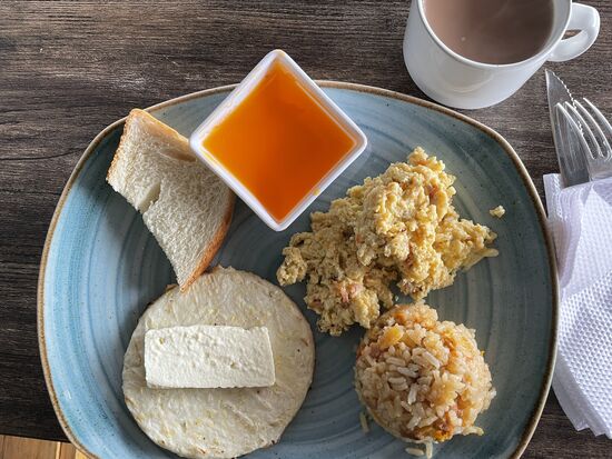 Typisches Frühstück mit Rührei, Reis, Arepa, Käse, Brot und Fruchtgelee