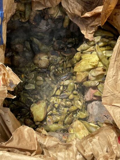 Statt in der Erde wird hier in einem grossen Sack, umgeben von heissen Steinen und unter einem farbigen Tuch gekocht.