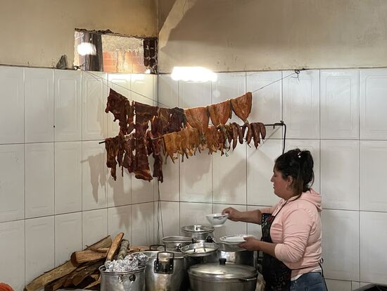 Über dem Herd hängt Fleisch und ausgenommene Fische zum Räuchern