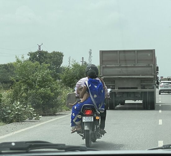 Das kleine Kind sitzt auf dem Schoss der Mutter und wird lässig mit einer Hand gehalten.
