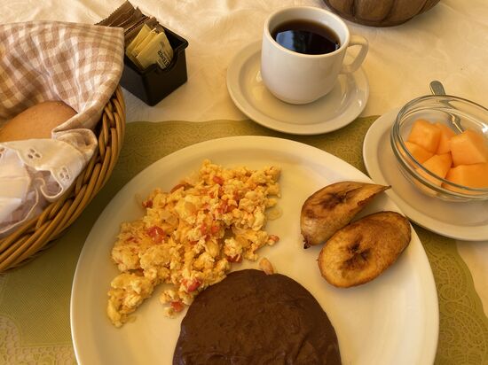 Typisches Frühstück: Rührei mit Tomaten und Zwiebeln, dazu Frijoles (Bohnenpuree) und gebratene Bananen, Papaya, Brot und Kaffee