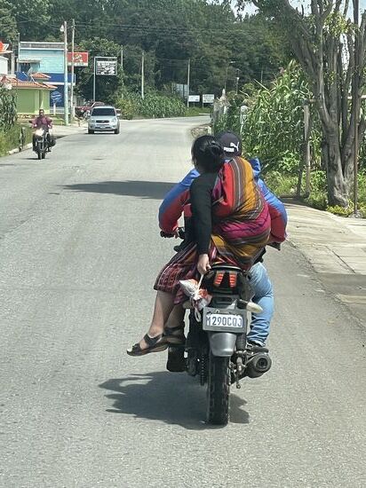Eine junge Familie unterwegs. Im Tuch auf dem Rücken der Frau liegt ein Baby