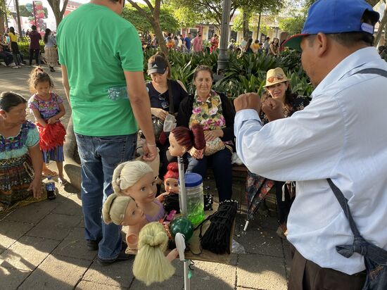 Er verkauft Haargummis und zeigt was für Frisuren man damit machen kann.