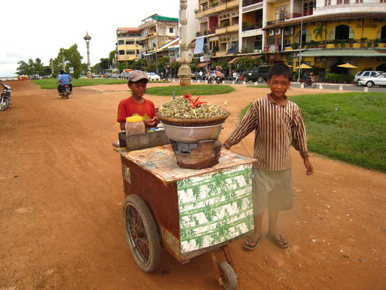 Die zwei Buben verkaufen Schnecken auf Holzkohle erhitzt/gekocht.