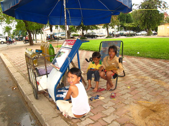 Tankstation: Die Kinder verkaufen Benzin fuer Mopeds und Motorraeder. Zum Zeitvertreib wird "geschnapst", der Kleine spielt mit dem Handy.