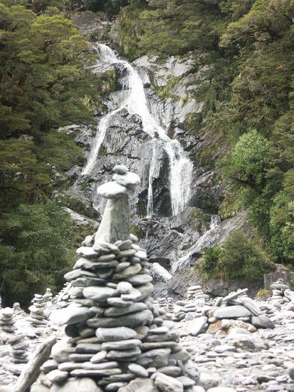 Ein Wasserfall mit Steinmännchen beim Haast Pass
