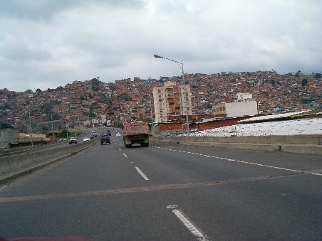 Autobahn mit Favelas im Hintergrund