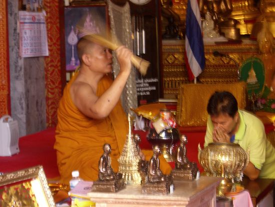 Ein Moench segnet grade ein paar Thais