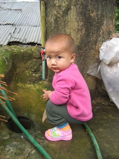 Kind im Mao-Dorf, dass gerade versucht, sich das Essen vom Mund abzuwischen