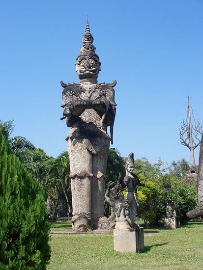 Der Gigant Koumphan traegt die bewusstlose Soumountha in seinen Armen. Das Motiv entstammt der bekannten Geschichte Sinxay, in der die Schoenheit vom Koenig der Riesen entfuehrt wird. Da sie unzaehlige Jahre an seiner Seite verbringt, moechte sie, als Sinxay schliesslich zur Rettung kommt, gar nicht mehr fort...