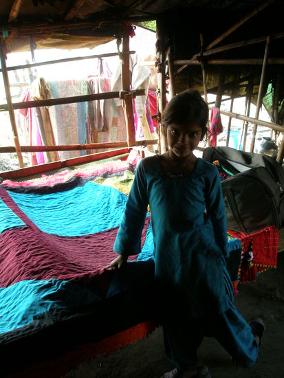 eines der indischen Maedchen von dem Fluechtligsdorf. Im Hintergund sieht man die Decken, die sie verkaufen und damit Schulgeld fuer die Kinder bezahlen koennen. Ob die Milch, die ich gependet habe nicht auch weiterverkauft wird steht in den Sternen!