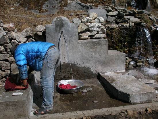 ein Dorfbewohner beim waesche waschen mit dem frischen, kalten Wasser
