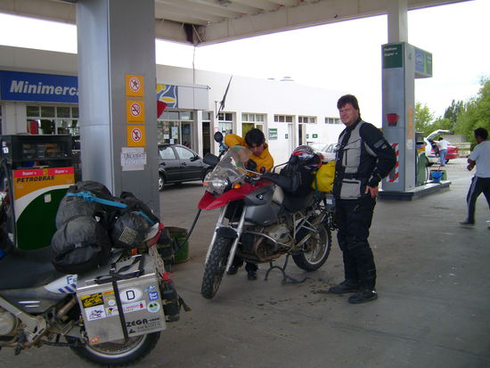 Der Tankwart ist konzentriert bei der Arbeit.... trotzdem schwappt Benzin ueber den Motor.