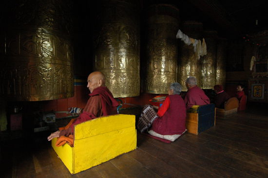 Geduldig drehen Moenche und Nonne riesige Gebetsmuehlen in einer Gompa bei Darjeeling