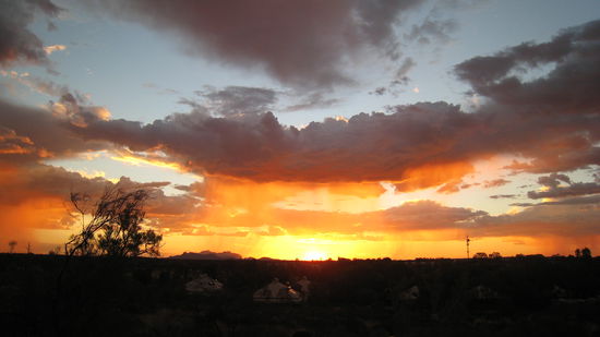 Die Sonne geht unter, und die Farbe vom Ayers Rock veraendert sich alle paar Minuten ...