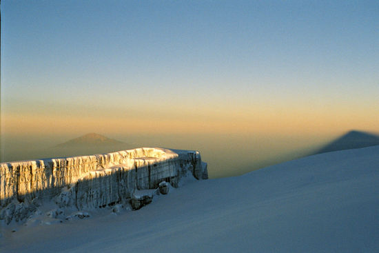 Auf dem Kibo-Gipfel; im Hintergrund links der Mount Meru, rechts der Schatten des Kibo