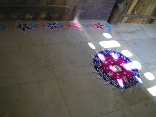 reste vom diwahli-fest letzte woche. ein blumenmantra aus buntem sand vor einer wohnungstuer in manans haus