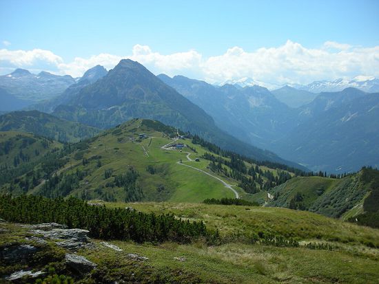 Folgen wir mit dem Auge dem Weg, erkennen wir kurz unterhalb des grünen Hügels (Mooskopf) unser Jausenziel: das Almstüberl.