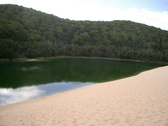 Eine riese Sandduene, mittendrin ein See, umgeben von einem Wald...
