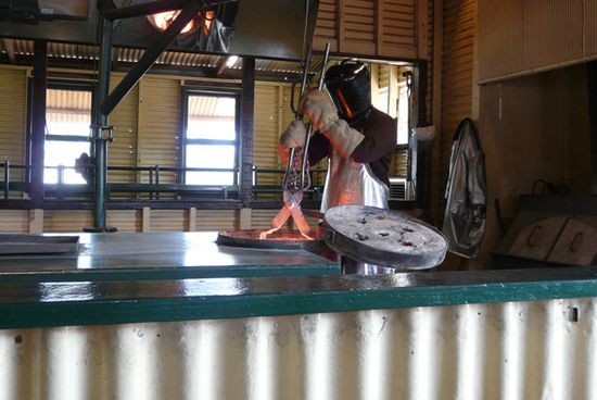 Der Behälter mit dem flüssigen Gold wird aus dem Schmelzofen gehoben
