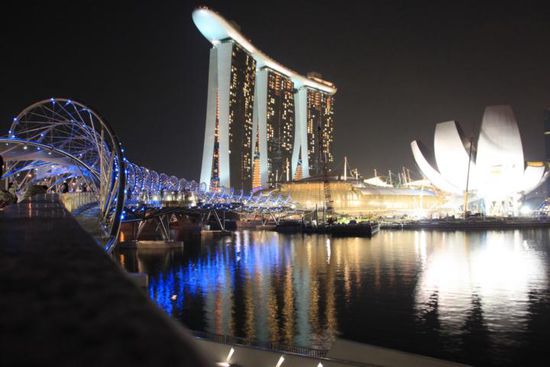 Das Marina Bay Sands Hotel bei Nacht. Davor, noch im Bau, die augehende Lotusblüte, die einmal ein Open-Air-Theater beherbergen wird.