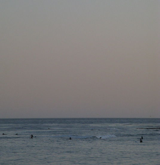 Es ist schon fast dunkel. Aber die Surfer haben es noch immer nicht aufgegeben...