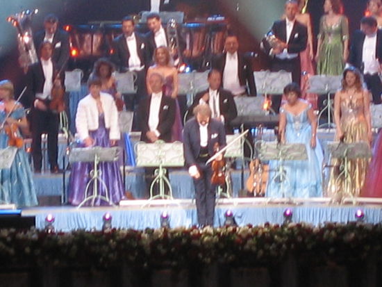 Mit einer tiefen Verbeugung vom Meister Andre Rieu begruesst. Im Hintergrund sein Damenorchester.